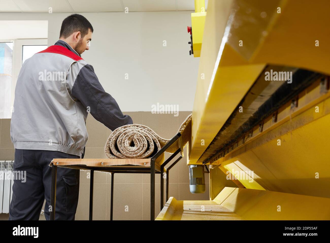 Man operating carpet automatic washing machine in professional laundry service Stock Photo