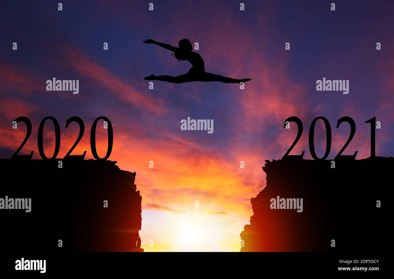 2021 New Year concept with silhouette of courageous girl jumping over cliff with dramatic sunset or sunrise background and copy space. Concept of goin Stock Photo