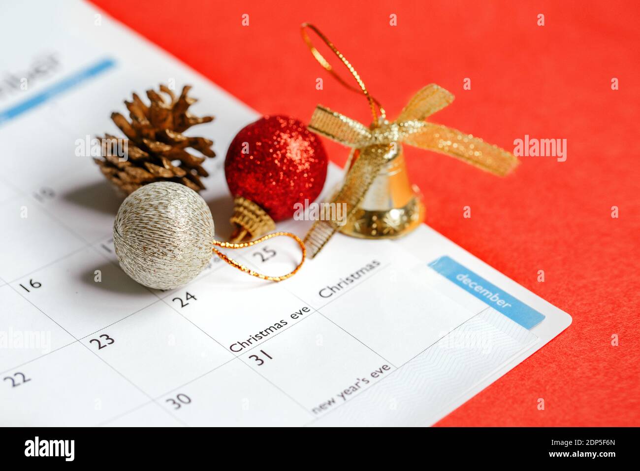 Page of planner calendar opened on December 24 Christmas holiday. Flat lay calendar with New Year or Christmas festive ornaments, toys, pine cone. Stock Photo