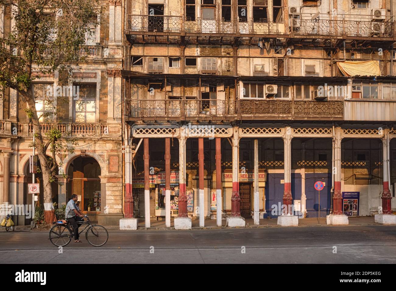 A cyclist passes crumbling Esplanade Mansion, originally Watson's Hotel,  built 1867-69; Kala Ghoda, Fort. Mumbai, India Stock Photo