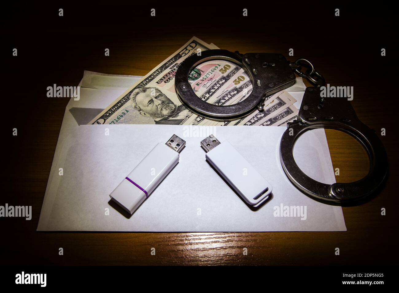 Envelope with an American Dollars Handcuffs and Two USB Drives on the Table closeup Stock Photo