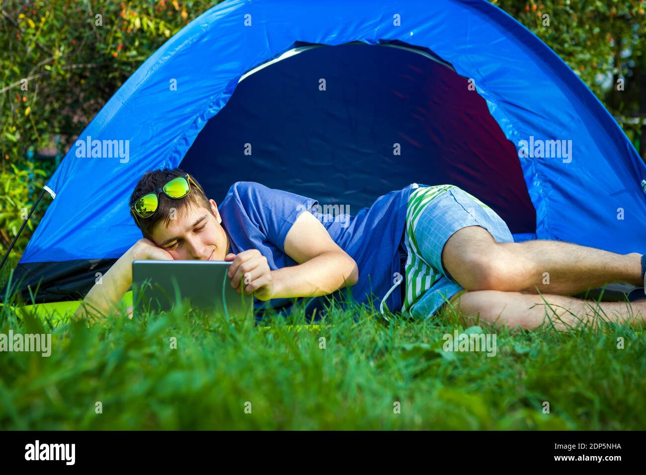 Young Man with a Tablet Computer in the Tent on the Nature Stock Photo