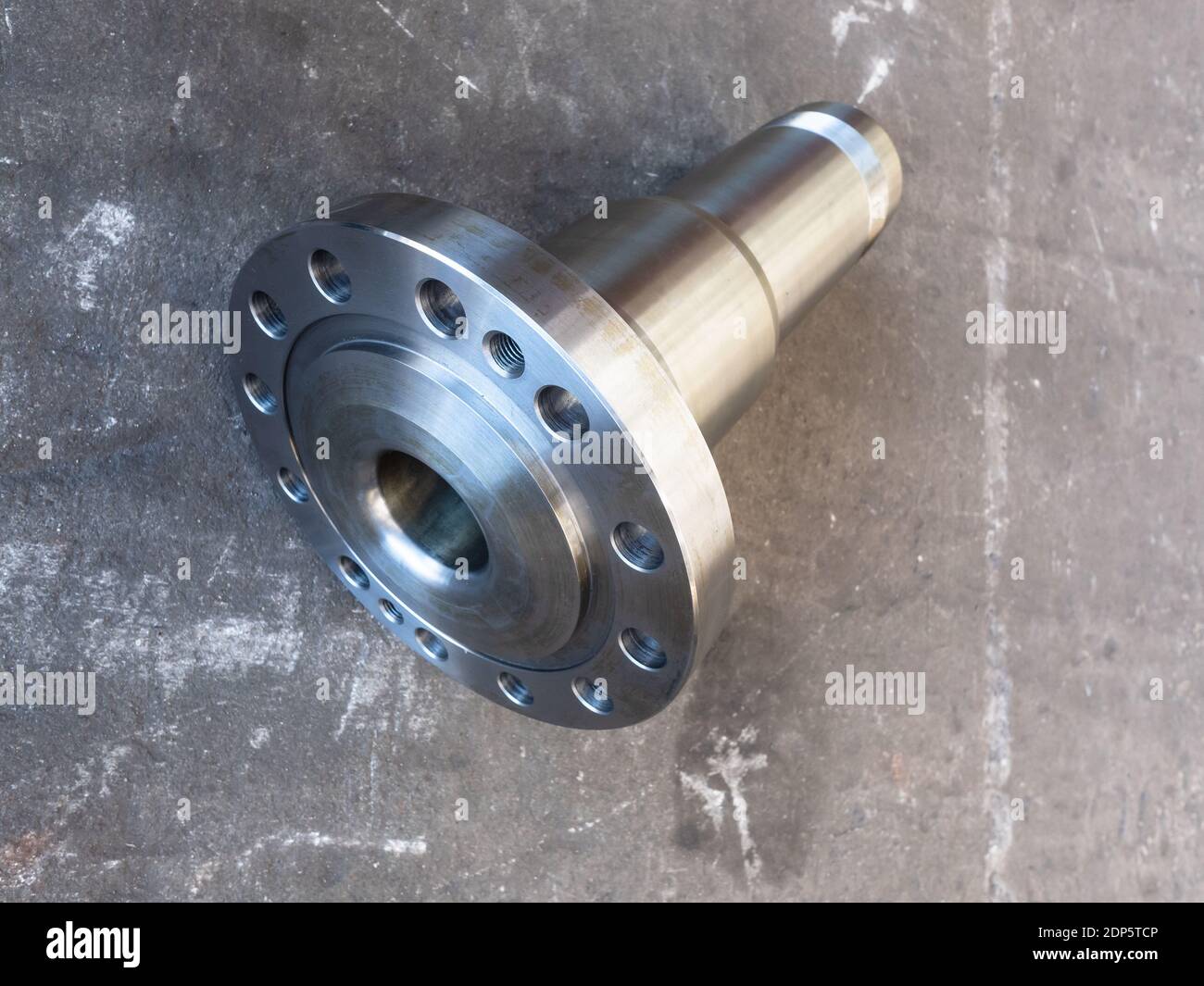Stainless steel, heavy duty industrial stub shaft on a dirty concrete floor. Stock Photo