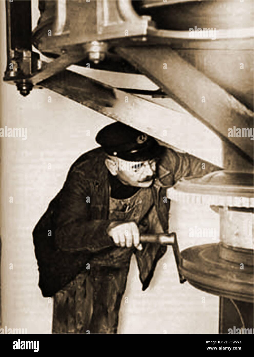 Adjusting the clockwork mechanism of a lighthouse lamp, a task that used to be regularly carried out before the automation of British lighthouses. Stock Photo