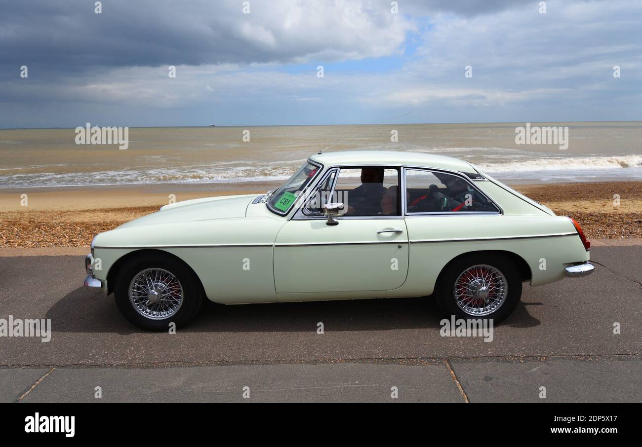 Classic Whie MGB GT Motor Car parked on seafront promenade with beach and sea in background. Stock Photo