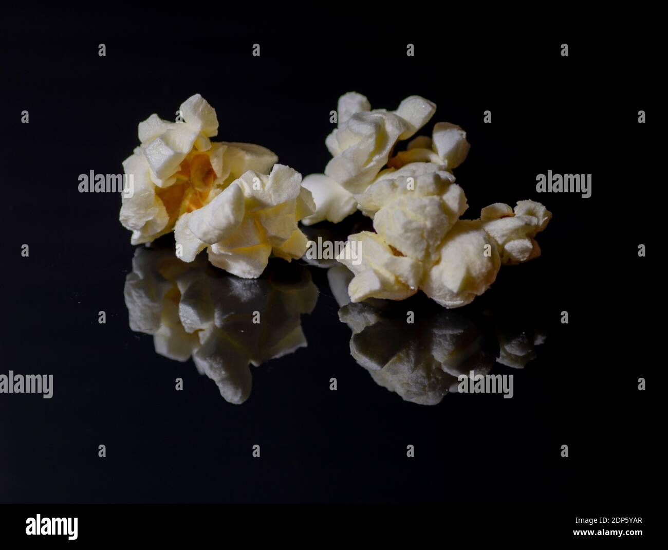 Popped popcorn isolated on black background. Reflection. Close up. Macro. Stock Photo