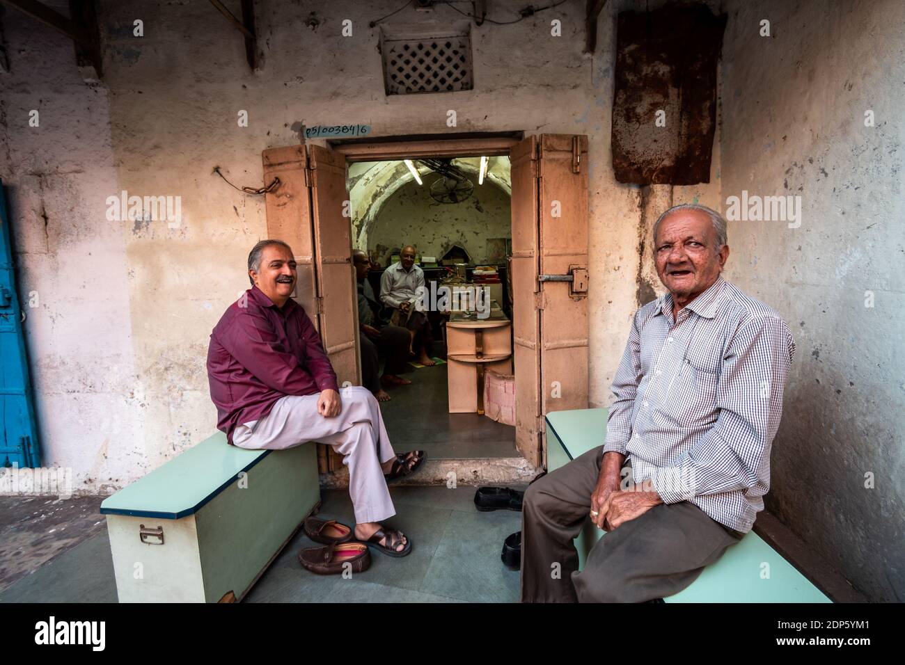 Jamnagar, Gujarat, India - December 2018: Elderly Indian men sitting outside a shop and having a conversation while hanging out. Stock Photo