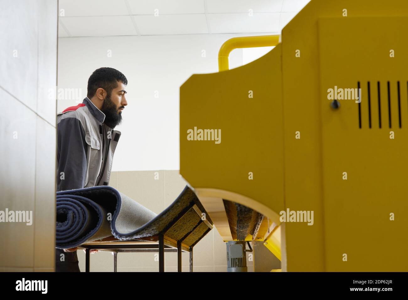 Man operating carpet automatic washing machine in professional laundry service Stock Photo