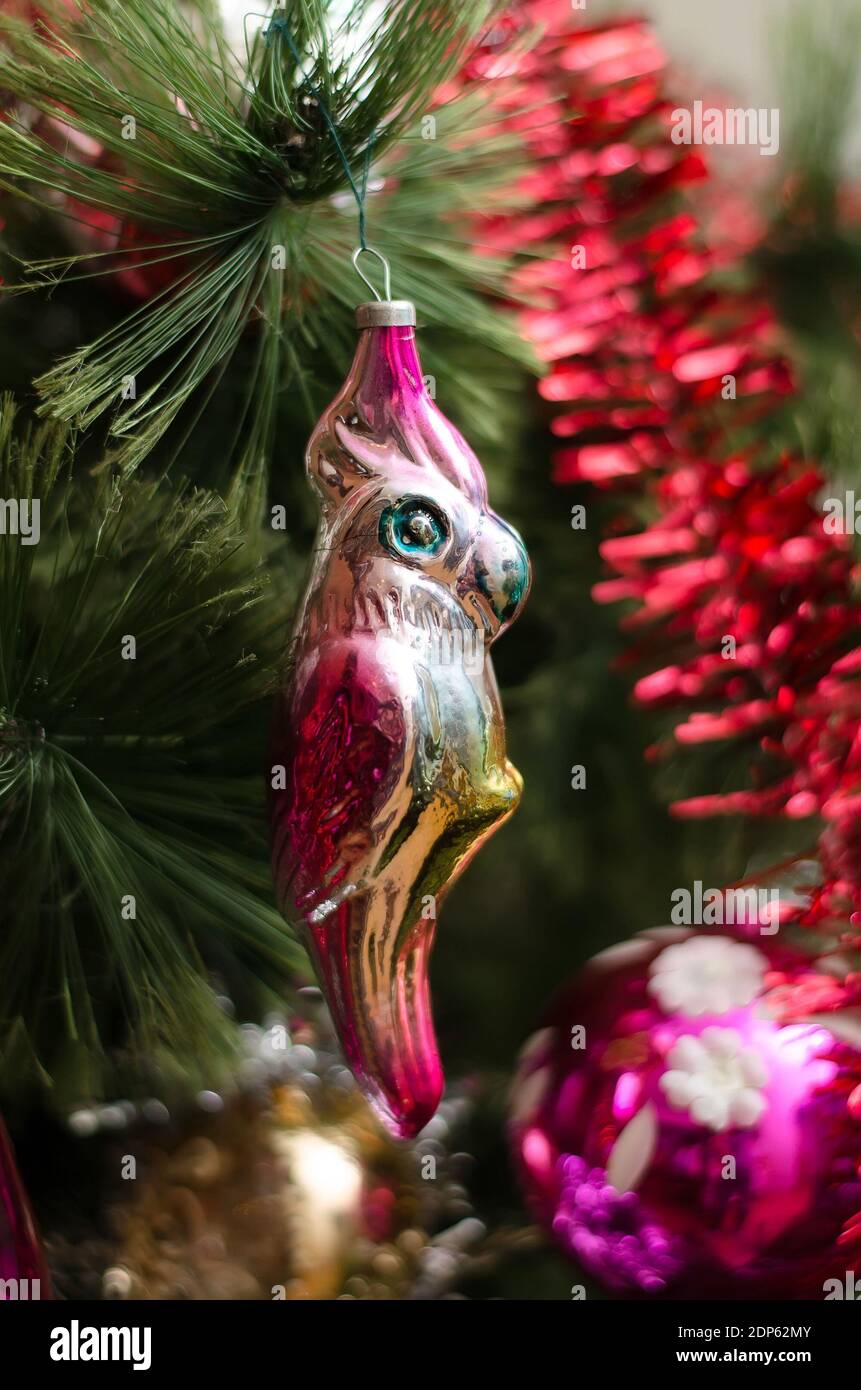 Colorful parrot made of glass on the Christmas tree among decorations, garlands and balls Stock Photo