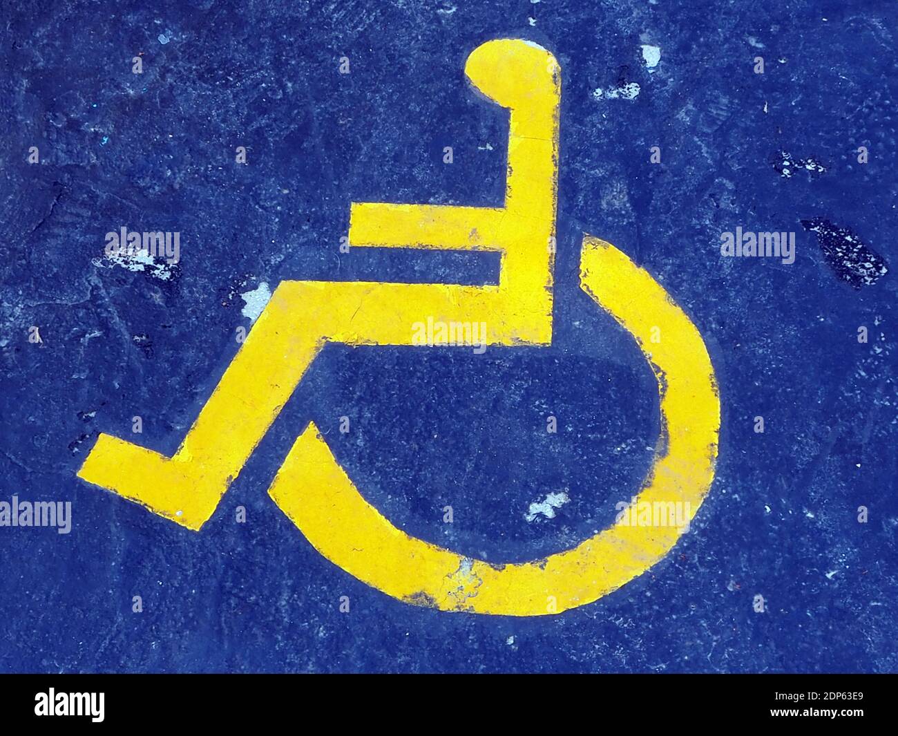 Yellow disabled-person sign marking a space at a parking lot, on a blue background at a marina in Greece Stock Photo