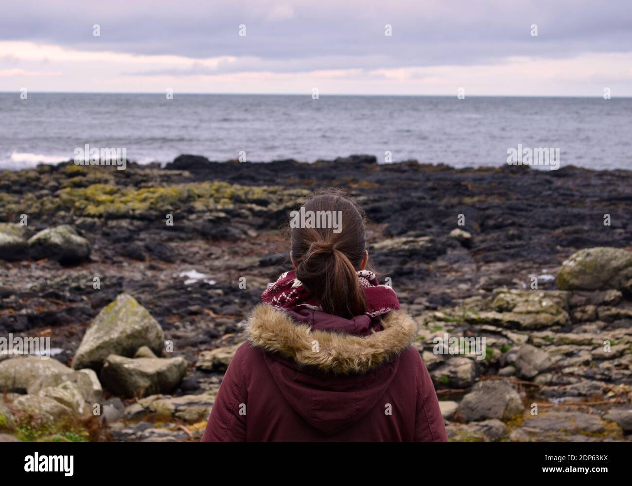 Solo traveller woman looking at the see in Giant's Causeway, Ireland Stock Photo