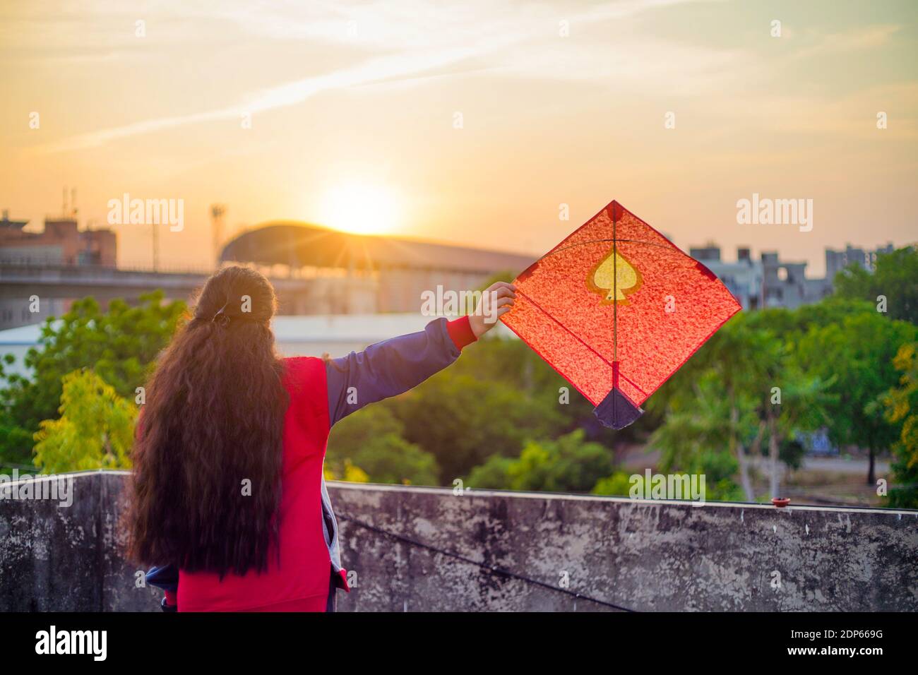 Young woman holding aloft colorful paper and wood kite against a blurred background  setting sun on the indian kite festival of makar sankranti or Stock Photo -  Alamy