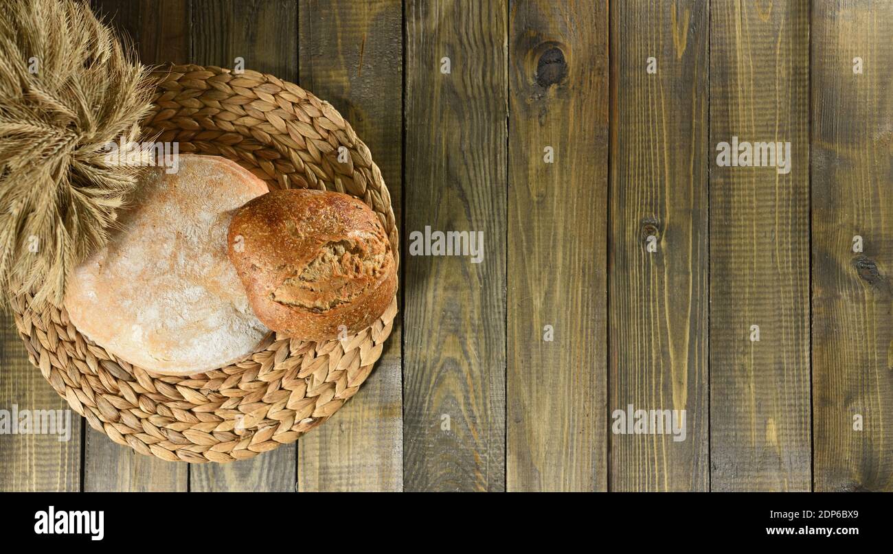 Two round loaves of bread and ears of wheat top view as background Stock Photo