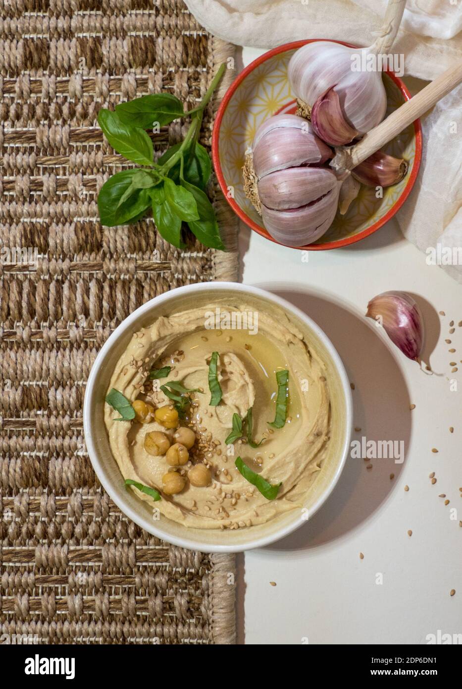 Bowl with freshly made, creamy hummus with chickpeas, basil and garlic isolated on colourful background Stock Photo