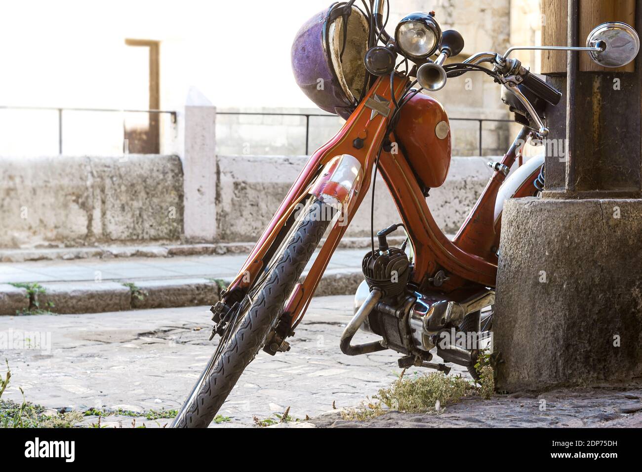 old and very old motorcycle leaning on a column in the city of Leon in Spain Stock Photo