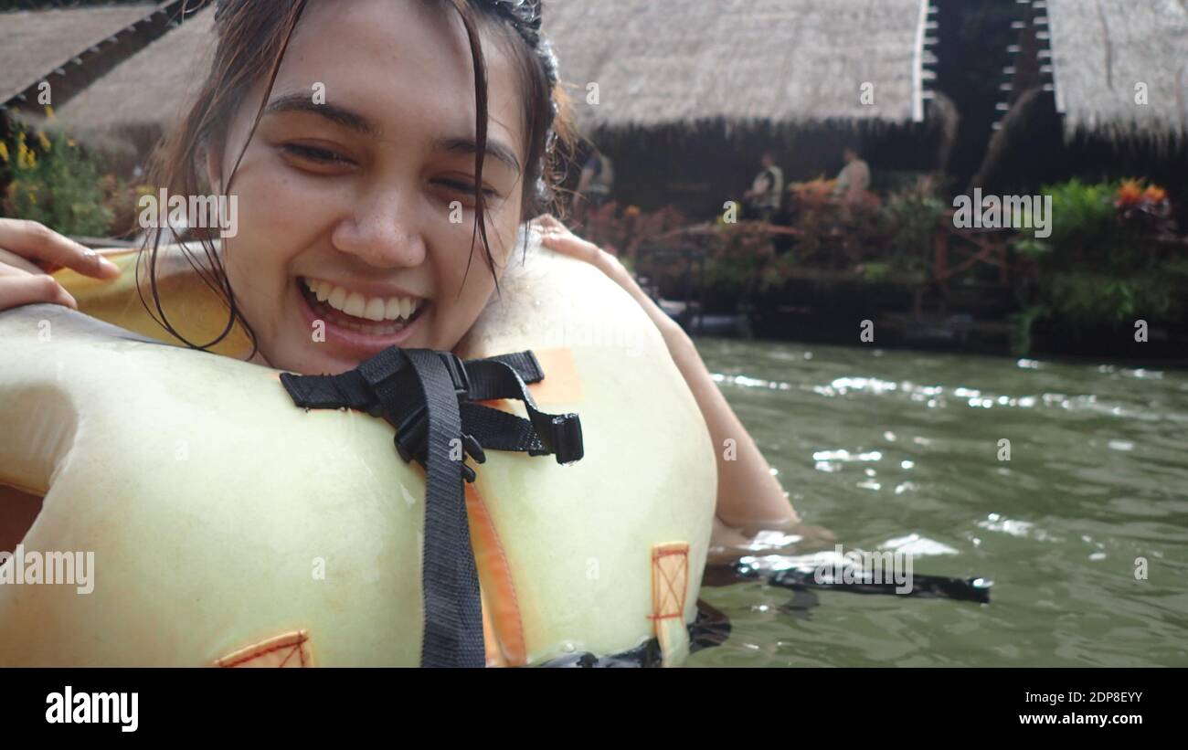 Beautiful Woman Wearing Life Jacket While Swimming In Lake Stock Photo
