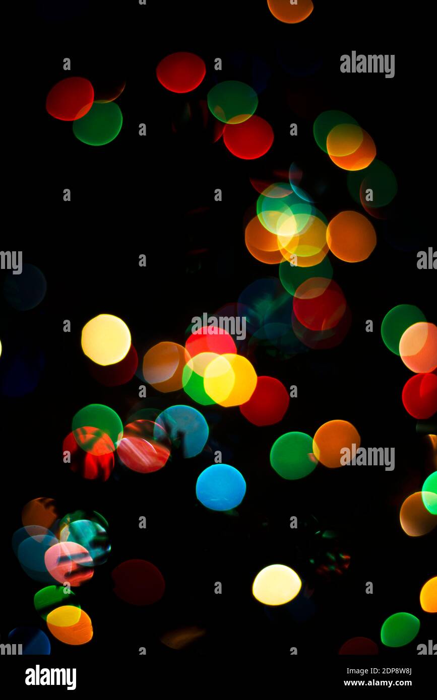 The colored lights are out of focus. Bokeh multicolored on a black background. New Year's themes. Template for greeting postcards text. Stock Photo