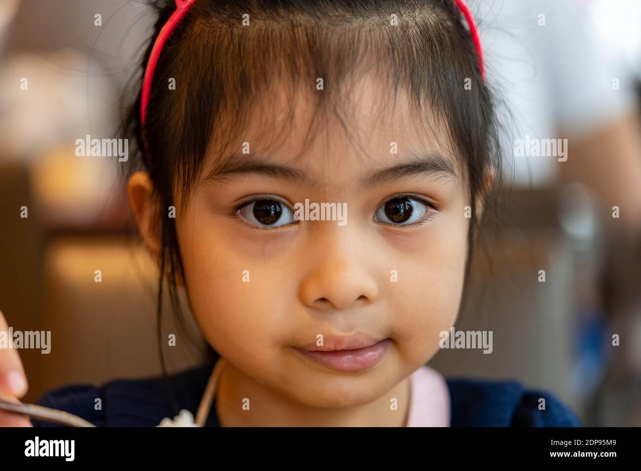 Close up shot of a female asian child serious while looking at camera. Pretty asian child with big eyes Stock Photo
