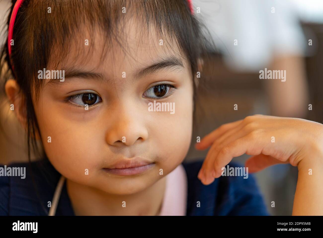 Close up shot of a female asian child serious and observing. Pretty asian child with big eyes Stock Photo