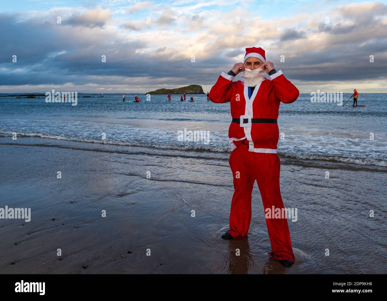North Berwick, East Lothian, Scotland, United Kingdom, 19th December 2020. Paddle Boarding Santas for charity: a local community initiative by North Berwick News and Views called 'Christmas Cheer' raises over £5,000 funds for families in need. Pictured: Organiser, Dave McGregor dressed in a Santa costume Stock Photo