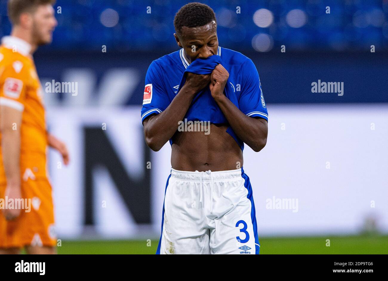 Gelsenkirchen, Germany. 19th Dec, 2020. Football: Bundesliga, FC Schalke 04 - Arminia Bielefeld, Matchday 13 at Veltins Arena. Schalke's Hamza Mendyl wipes the sweat from his face with his jersey. Credit: Guido Kirchner/dpa - IMPORTANT NOTE: In accordance with the regulations of the DFL Deutsche Fußball Liga and/or the DFB Deutscher Fußball-Bund, it is prohibited to use or have used photographs taken in the stadium and/or of the match in the form of sequence pictures and/or video-like photo series./dpa/Alamy Live News Stock Photo