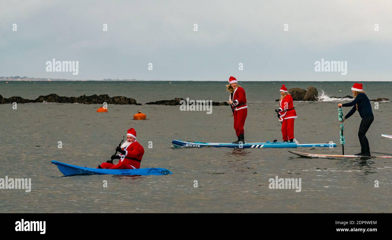 North Berwick, East Lothian, Scotland, United Kingdom, 19th December 2020. Paddle Boarding Santas for charity: a local community initiative by North Berwick News and Views called 'Christmas Cheer' raises over £5,000 funds for families in need. The paddle boarders are dressed in Santa costumes Stock Photo