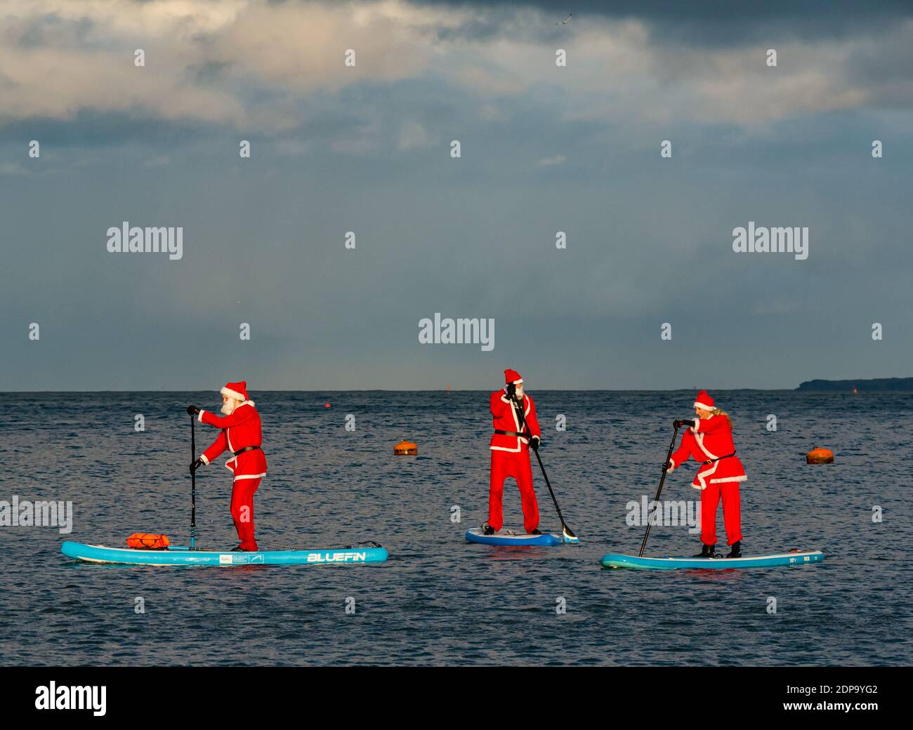 North Berwick, East Lothian, Scotland, United Kingdom, 19th December 2020. Paddle Boarding Santas for charity: a local community initiative by North Berwick News and Views called 'Christmas Cheer' raises over £5,000 funds for families in need. The paddle boarders are dressed in Santa costumes Stock Photo