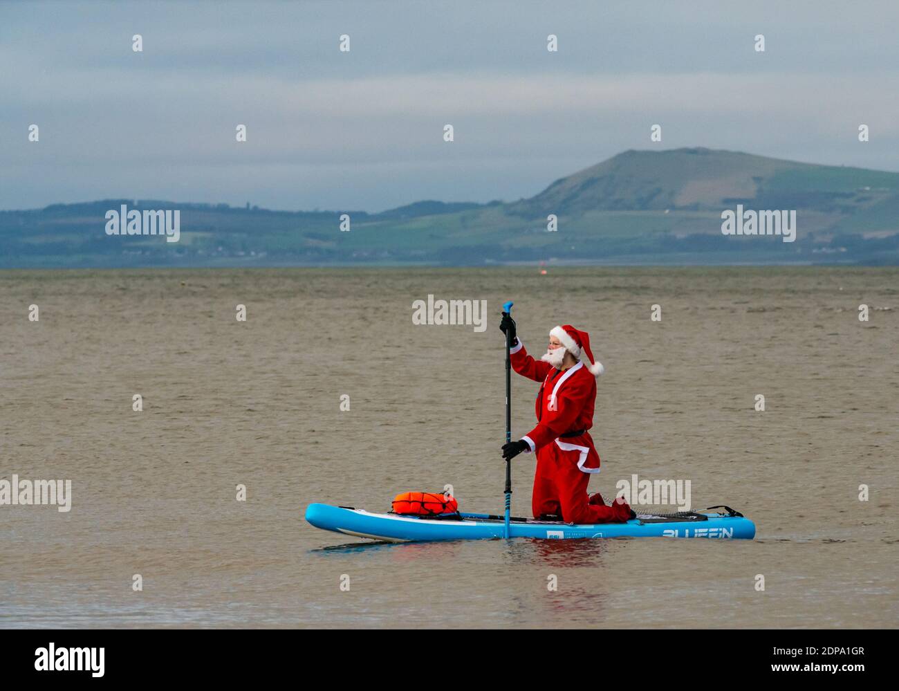 North Berwick, East Lothian, Scotland, United Kingdom, 19th December 2020. Paddle Boarding Santas for charity: a local community initiative by North Berwick News and Views called 'Christmas Cheer' raises over £5,000 funds for families in need. A paddle boarder dressed in a Santa costume Stock Photo