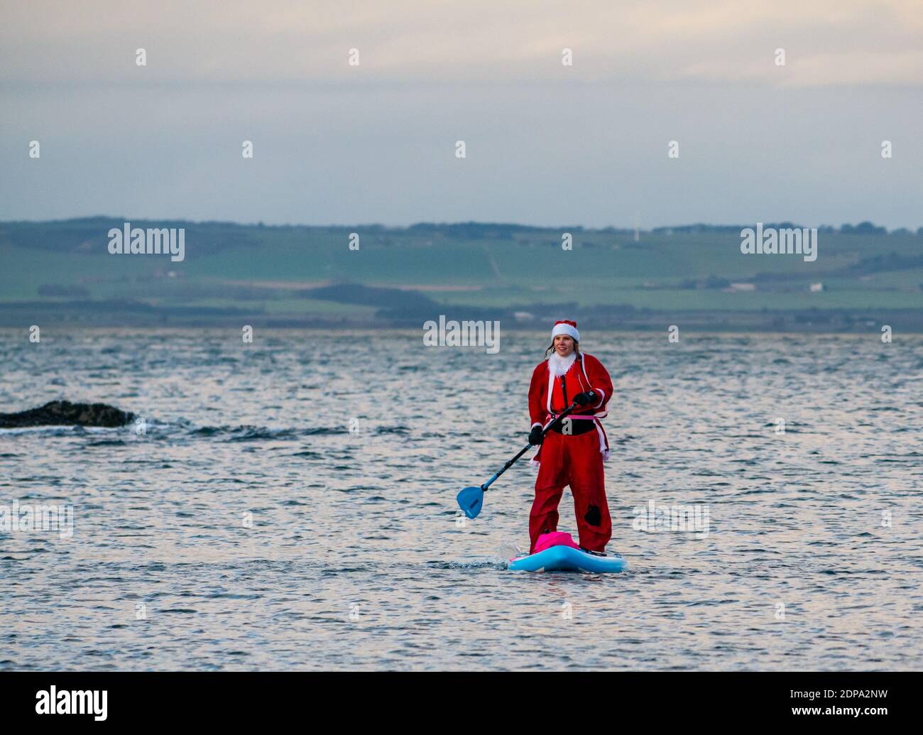 North Berwick, East Lothian, Scotland, United Kingdom, 19th December 2020. Paddle Boarding Santas for charity: a local community initiative by North Berwick News and Views called 'Christmas Cheer' raises over £5,000 funds for families in need. A paddle boarder dressed in a Santa costume Stock Photo