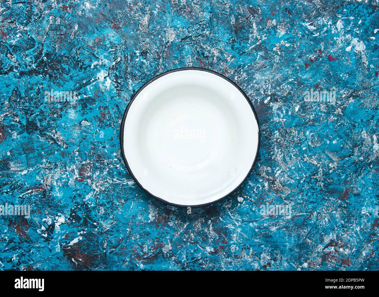 White enamel bowl on a blue concrete background. Top view Stock Photo