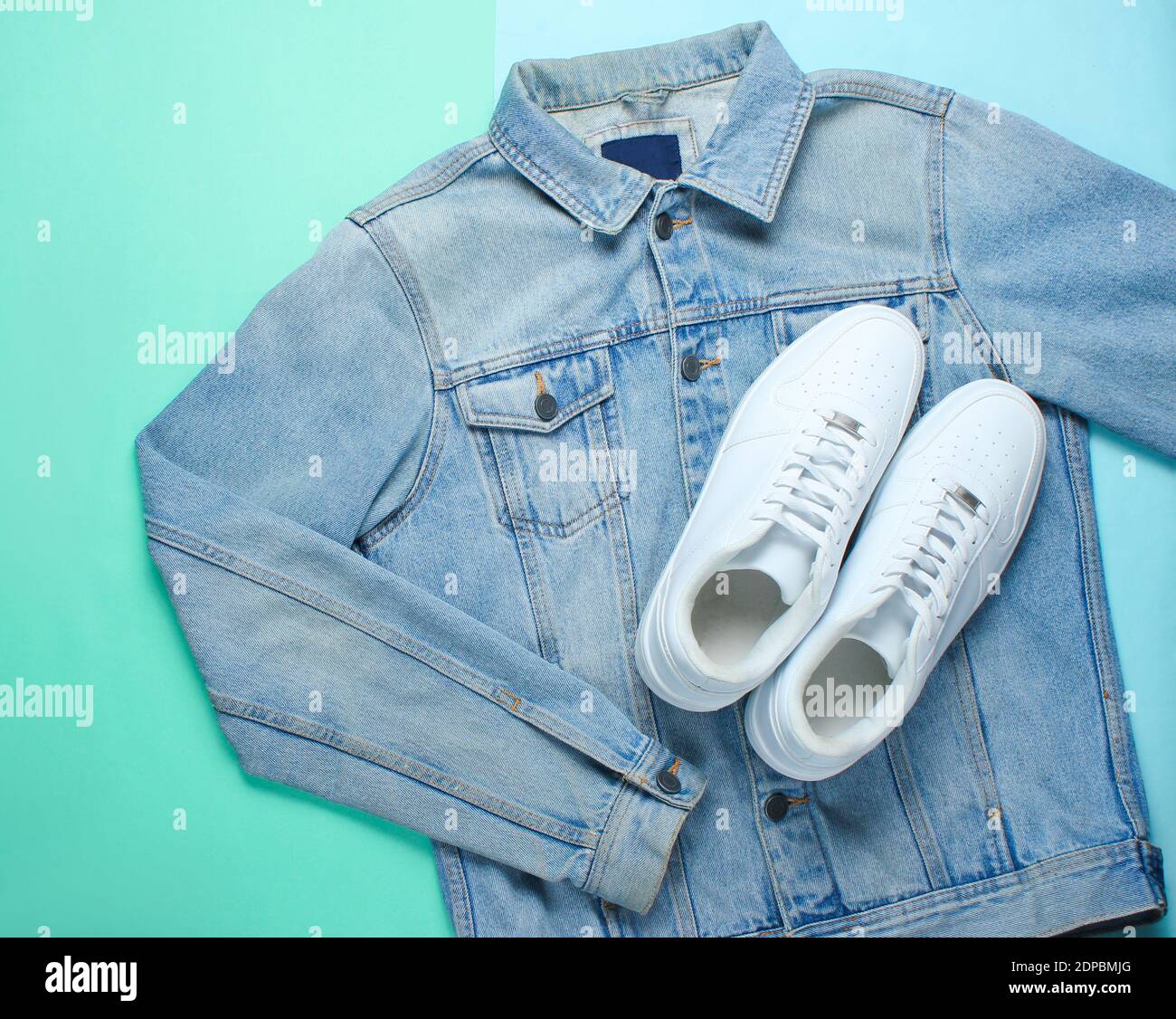 Flat lay style white hipster sneakers with a denim jacket on a pastel ...