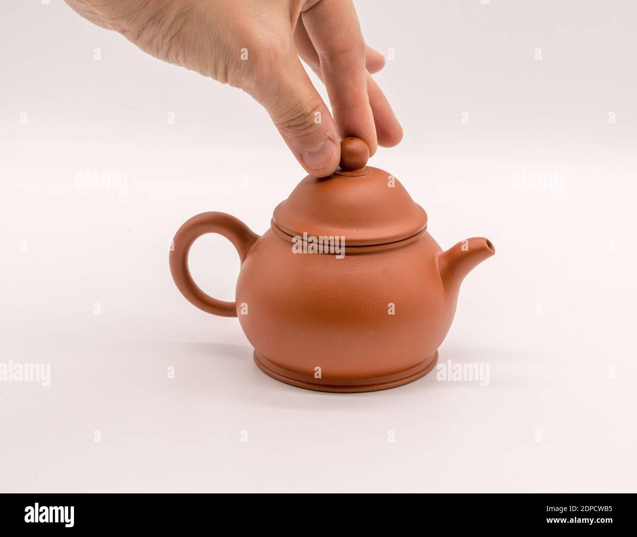 Cropped Hand Holding Lid Of Teapot Over White Background Stock Photo - Alamy