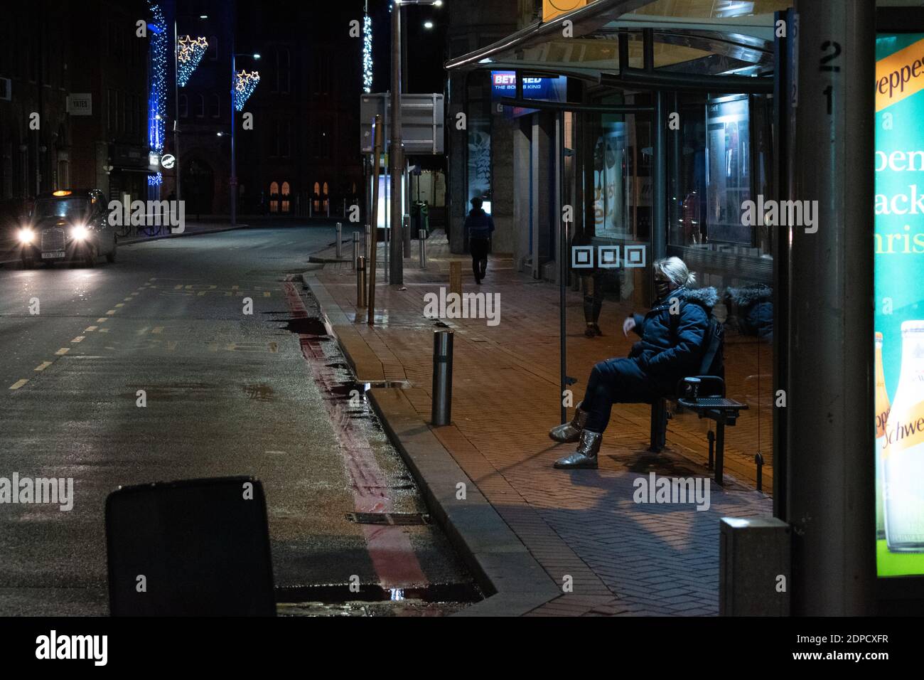 Woman waits for a bus at the bus stop in Friar street Reading. Stock Photo