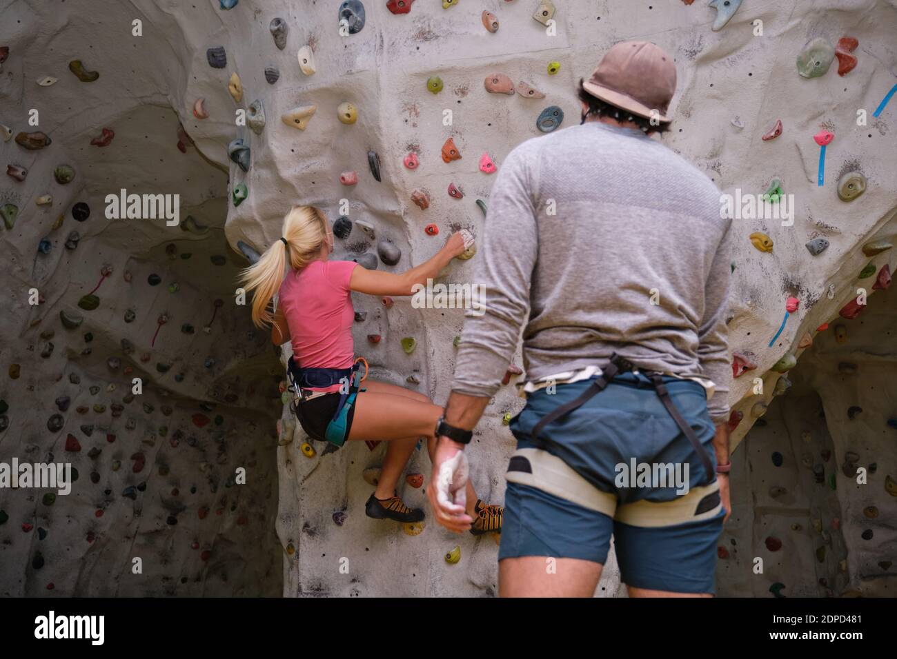 Two young friends climbing a wall on artificial rock climbing wall indoors. Extreme sports concept. Stock Photo