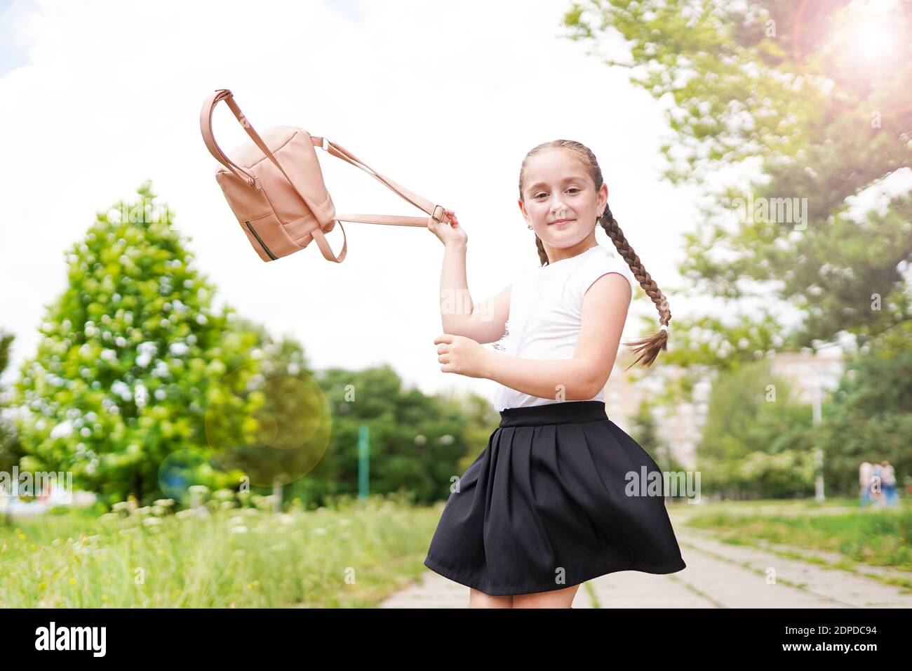 Happy smiling little girl throws up her backpack, outdoors in school  playground Stock Photo - Alamy