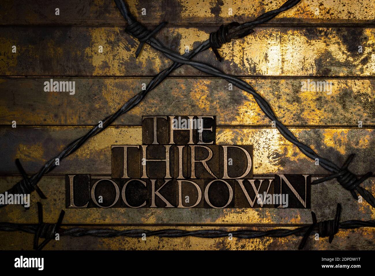 The Third Lockdown text on grunge textured copper and gold background enclosed by barbed wire Stock Photo