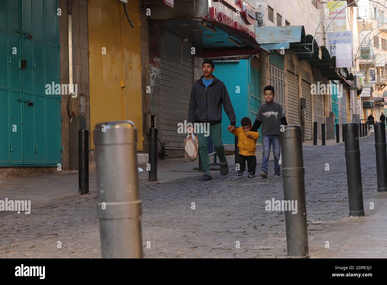 Bethlehem. 19th Dec, 2020. Palestinians walk on a street in the West Bank city of Bethlehem amid a lockdown, on Dec. 19, 2020. A full lockdown and curfew have been imposed in the West Bank and the Gaza Strip to curb the growing numbers of COVID-19 infections and deaths. Credit: Mamoun Wazwaz/Xinhua/Alamy Live News Stock Photo
