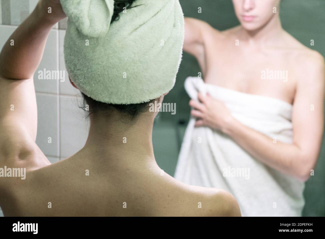 Young woman drying up her hair and body with the towels after a shower and body care in front of the mirror of the bathroom Stock Photo