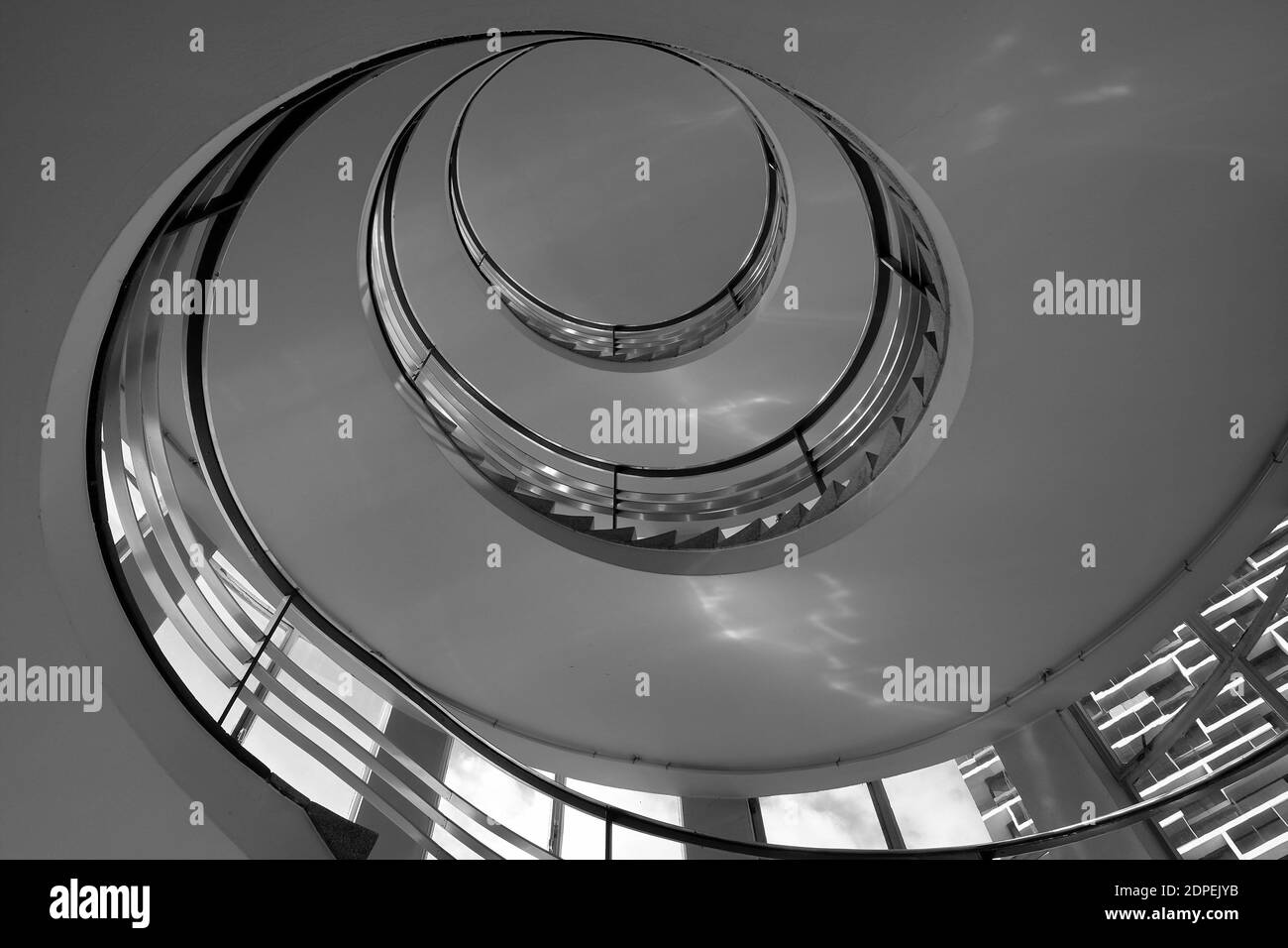 A greyscale low angle shot of the spiral staircase in the building Stock Photo