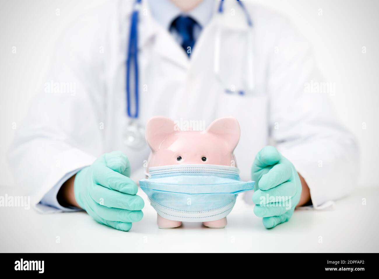 Doctor with piggy bank wearing face mask. Health costs, health insurance concept Stock Photo