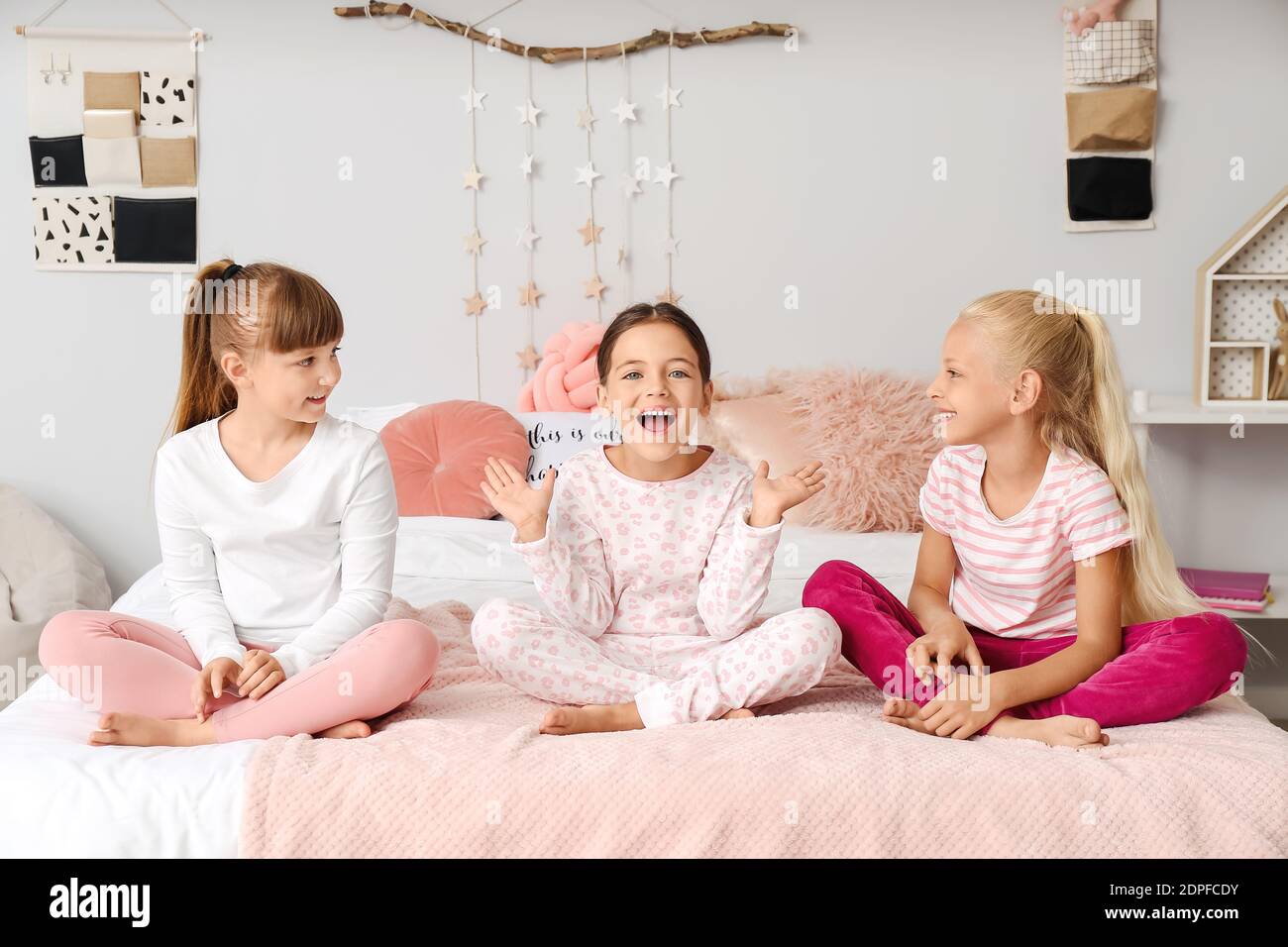 Cute little girls sitting on bed in pajamas at home Stock Photo - Alamy