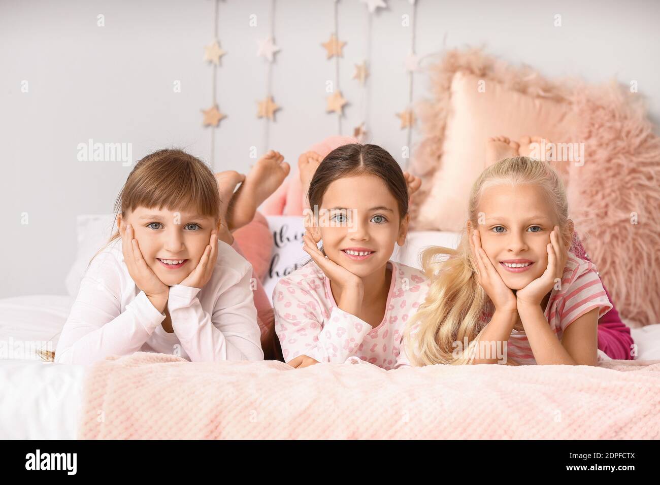 Cute little girls lying on bed in pajamas at home Stock Photo - Alamy