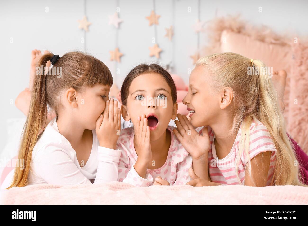 Cute little girls lying on bed in pajamas at home Stock Photo - Alamy