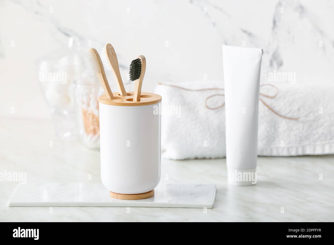 Holder with wooden toothbrushes and toothpaste on table in bathroom ...
