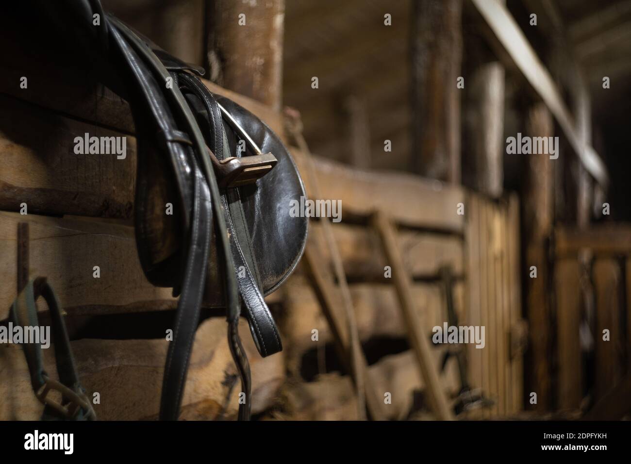leather horse saddle hanging on a fence in a stable with space for text Stock Photo