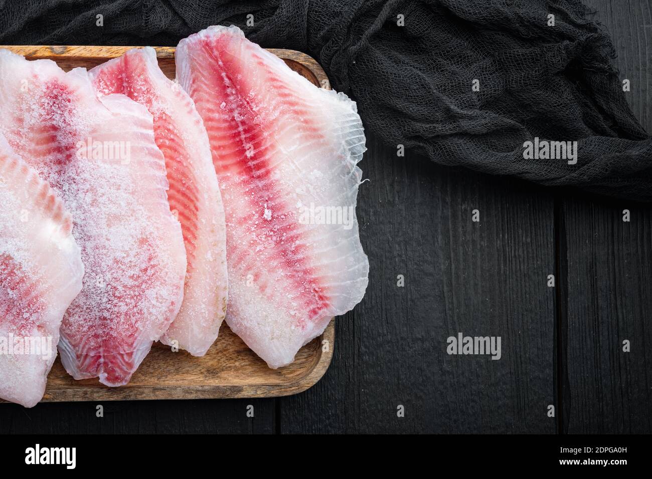 Fish Fillet Sets Frozen fish fillet set, on black wooden table, top view with copy space ...