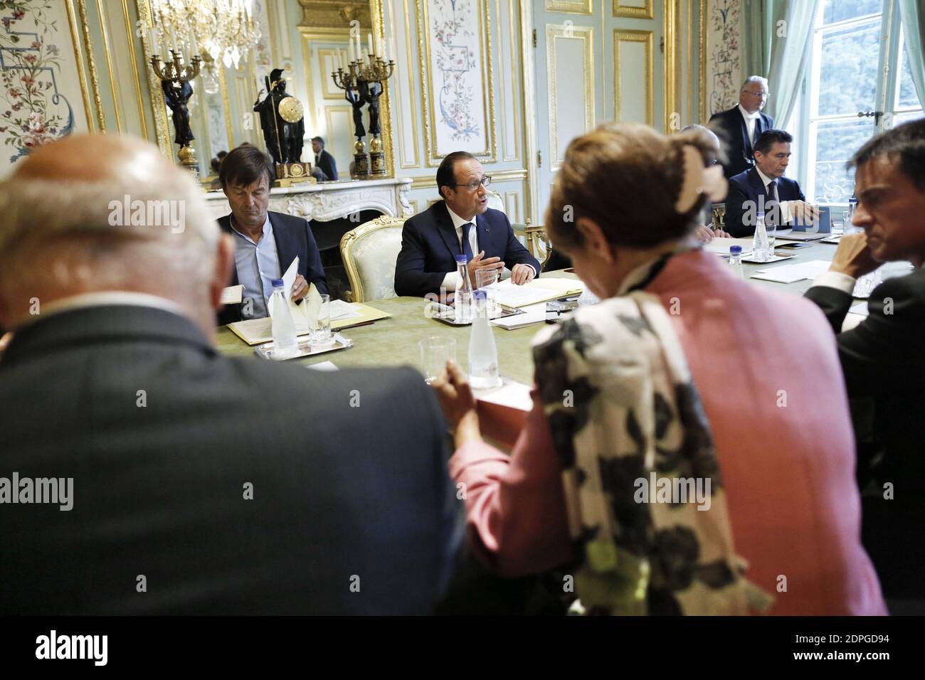 French President Francois Hollande (C) presides over a ministerial meeting including Prime Minister Manuel Valls (foreground, R), Minister of Ecology, Sustainable Development and Energy Segolene Royal (foreground, C), Minister of Foreign Affairs and International Development Laurent Fabius (unpictured), Minister of Finance and Public Accounts Michel Sapin (foreground, L), environmental activist and President Hollande's special envoy for the protection of the planet Nicolas Hulot (background, L) and COP21 special representative Laurence Tubiana (unpictured), in preparation for the COP21 Climate Stock Photo