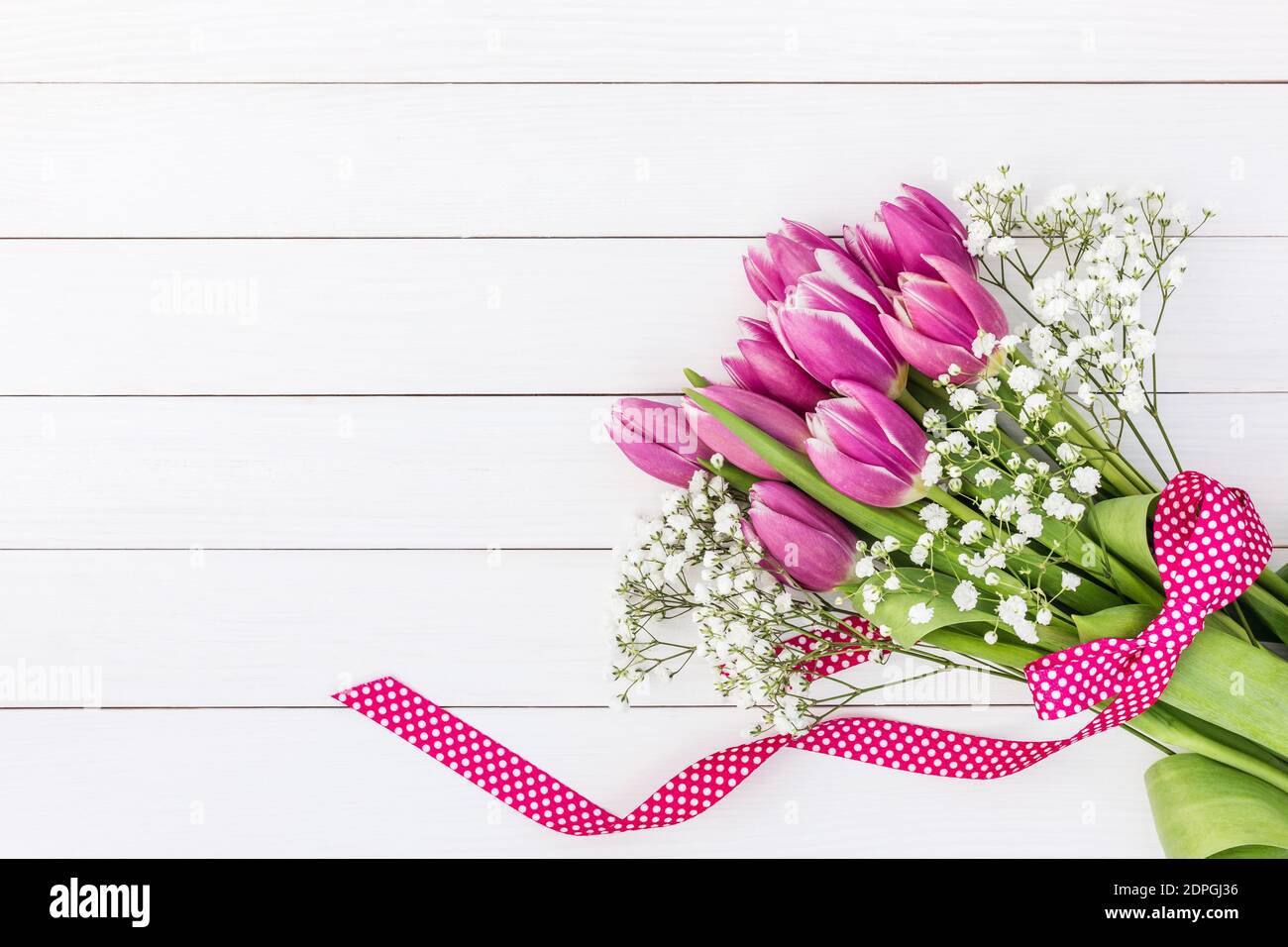 Bouquet of bright pink tulips and gypsophila decorated with ribbon on ...
