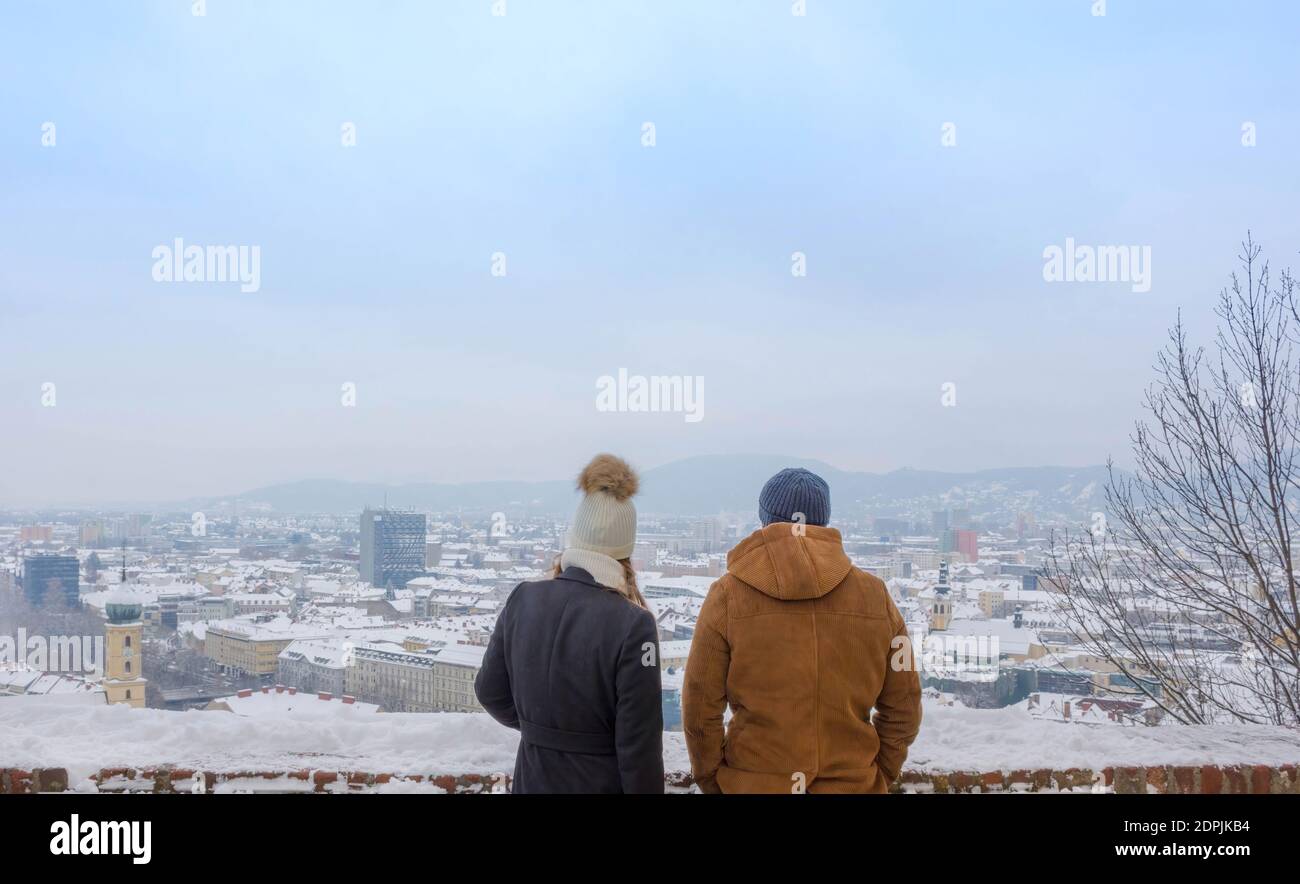 People on Schlossberg hill admiring the cityscape of Graz with historic and modern buildings, in winter after snow, Styria region, Austria Stock Photo