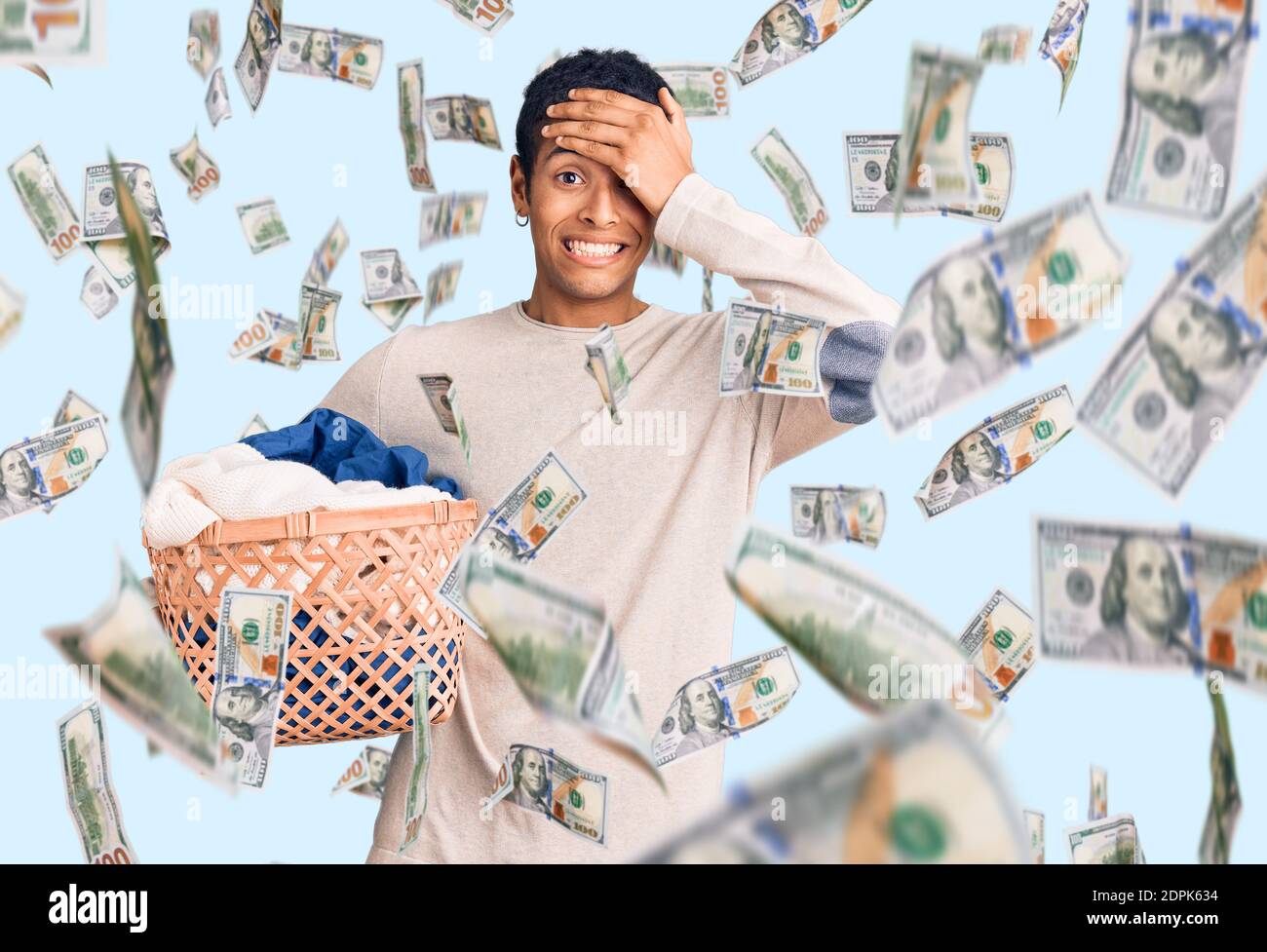 Young african amercian man holding laundry basket stressed and frustrated with hand on head, surprised and angry face Stock Photo